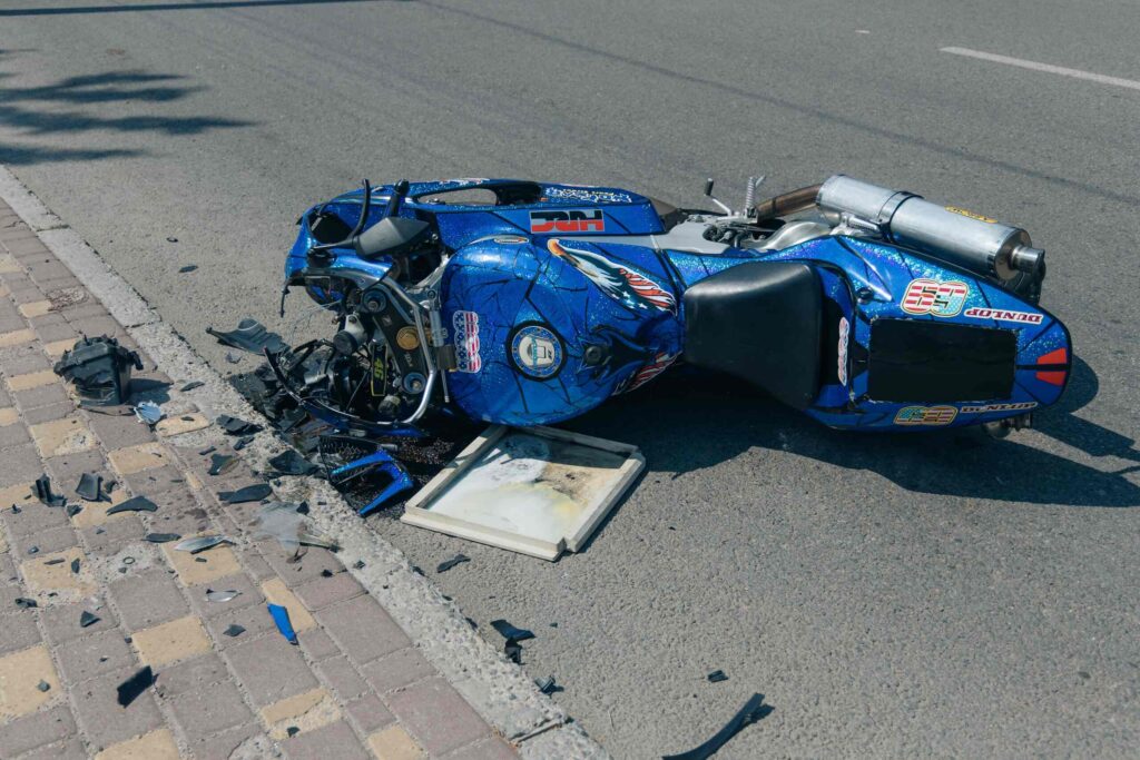 A crashed blue motorcycle lying on the asphalt after an accident causing Florida road rash injuries.