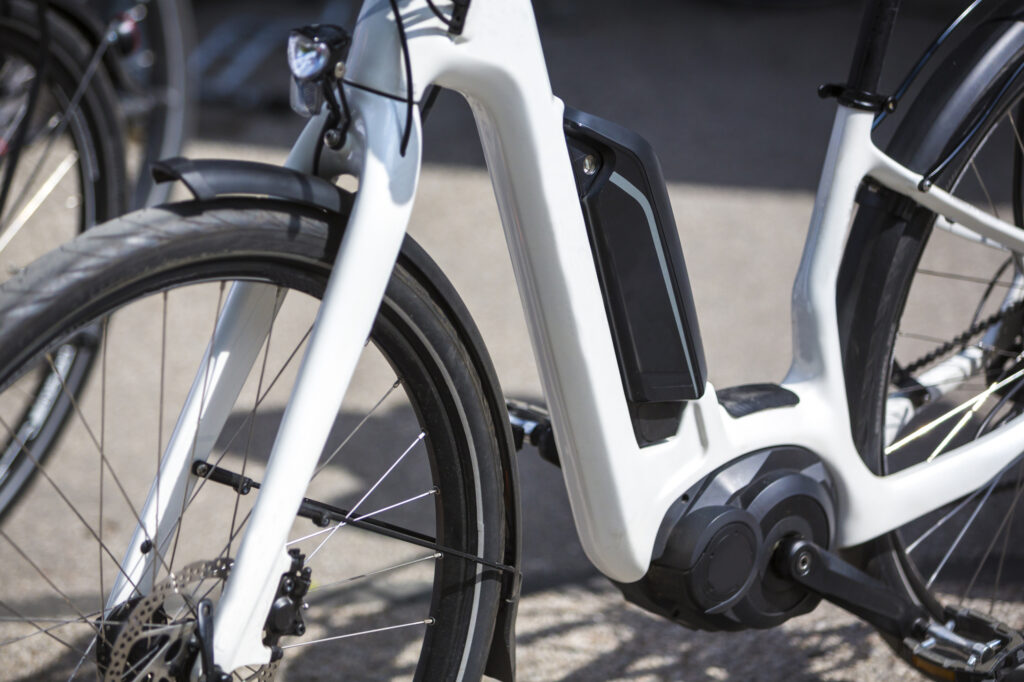 Close up view of a white electric bicycle showing the frame battery pack and motor.