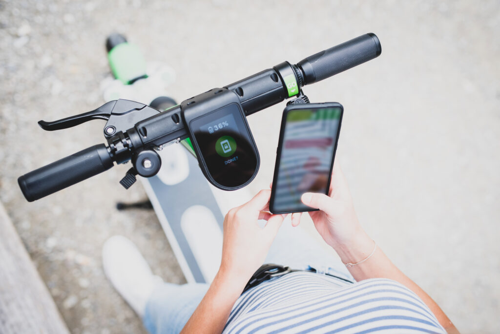 Rider using a smartphone to unlock an electric scooter using a mobile app.