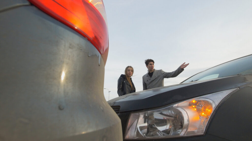 Two drivers discussing vehicle damage following a rear end car accident.