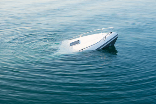 White motorboat sinking and partially submerged in calm water.
