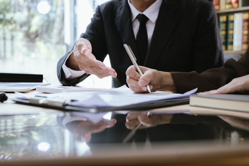 Lawyer in suit reviewing legal documents with a client at a desk.