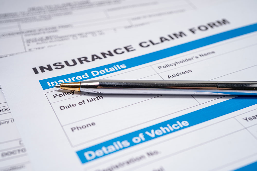Pen resting on an insurance claim form related to a car accident encourages documentation and claim filing.