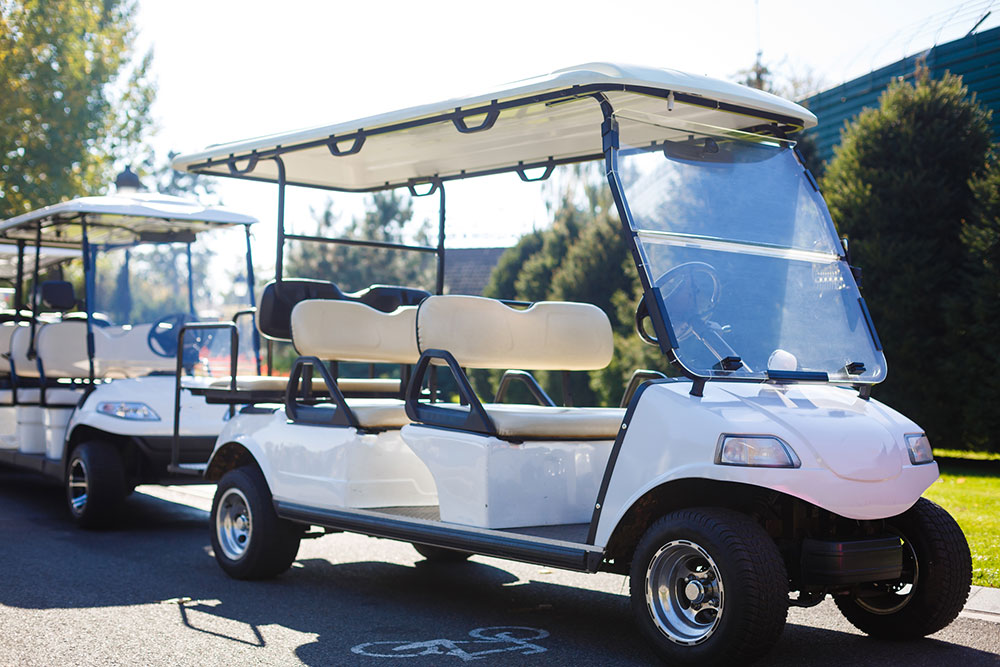 Golf cart parked on grass under a blue sky