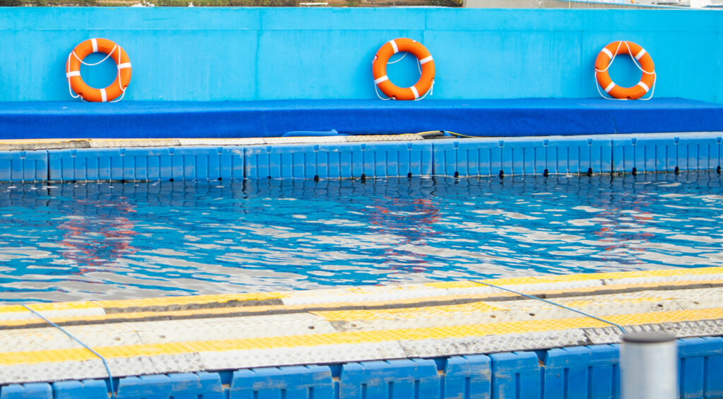 Lifebuoys mounted by a swimming pool representing water safety measures and drowning prevention