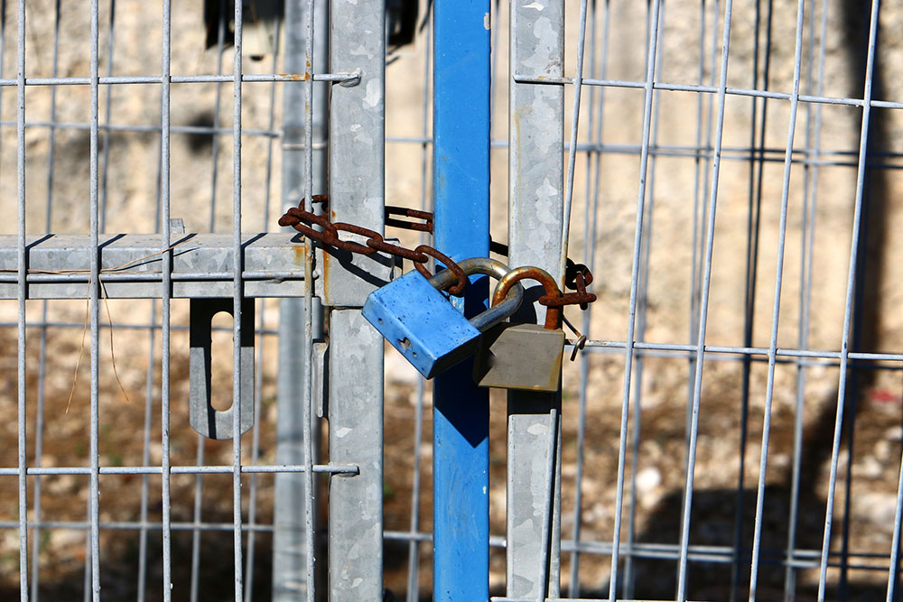 Padlock on a closed gate representing property security and restricted access conditions