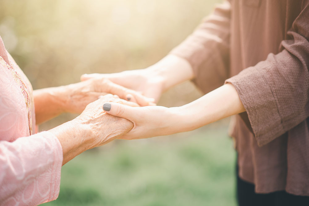 Older woman and younger woman holding hands in a supportive moment