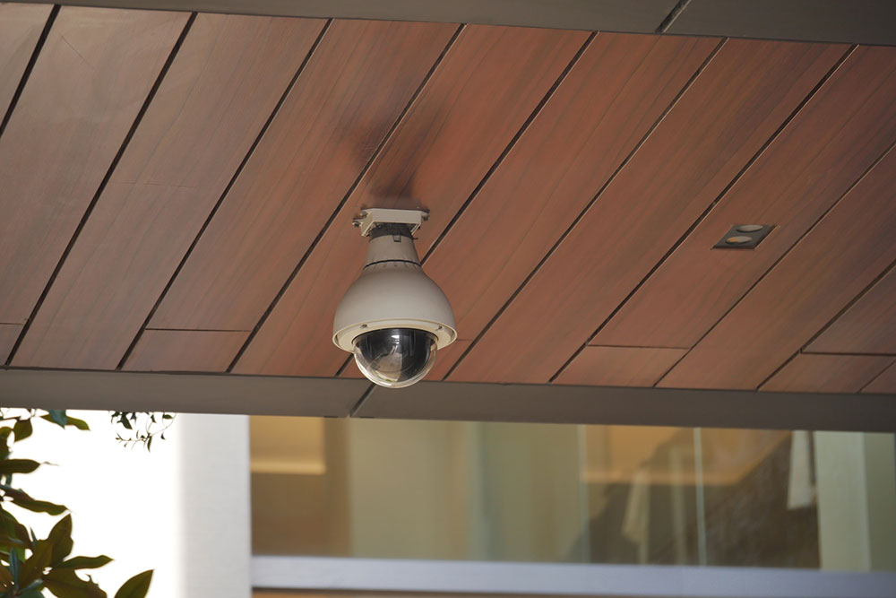 Security camera under a building roof representing surveillance and premises safety