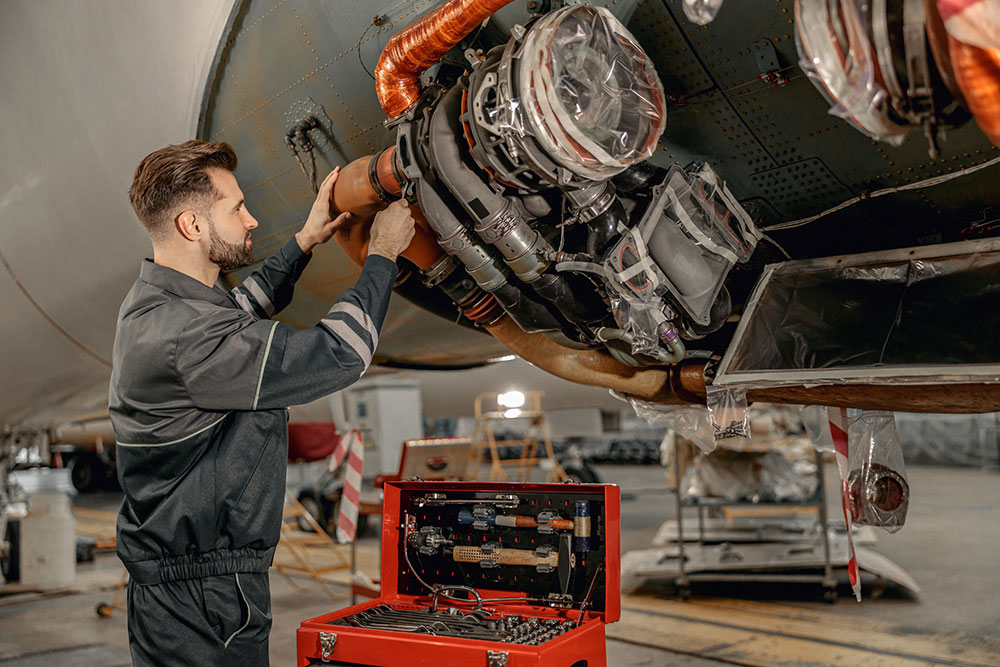 Aviation mechanic repairing an airplane inside a hangar during maintenance