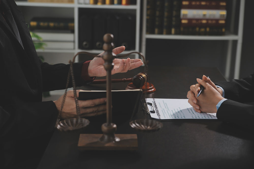 Female lawyers reviewing legal documents with a judge’s gavel and scales of justice on the desk