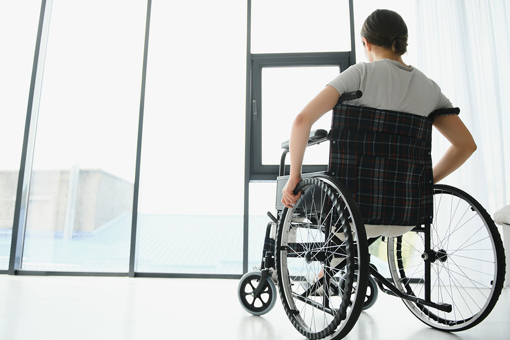 Young woman using a wheelchair at home in a living room after a life-changing injury