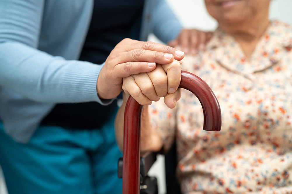 Caregiver supporting an elderly woman patient during assisted care in a nursing facility