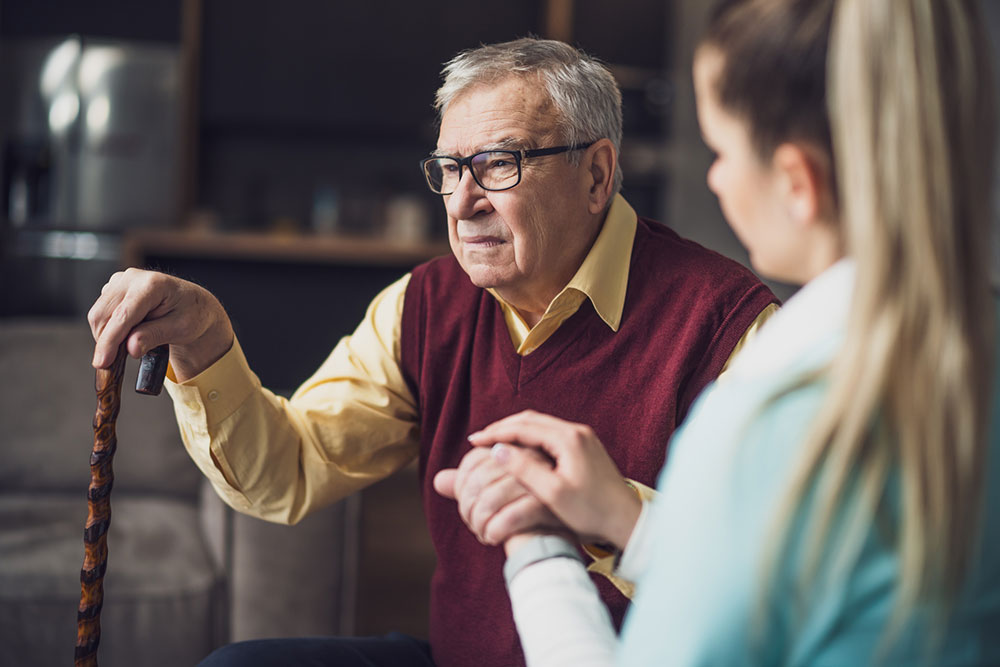 Elderly man receiving assistance from a caretaker during in-home or facility-based senior care