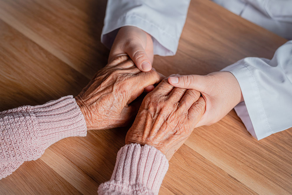 Doctor shaking hands with a senior patient in a clinic as encouragement and support