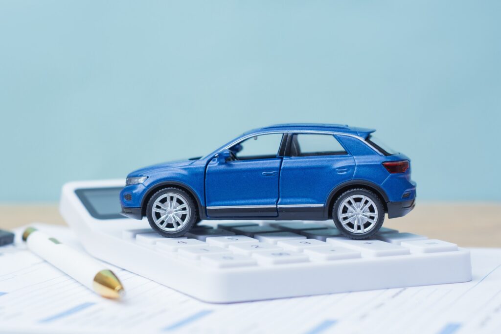 A toy car on a calculator representing how car insurance rates go up after an accident in Florida.