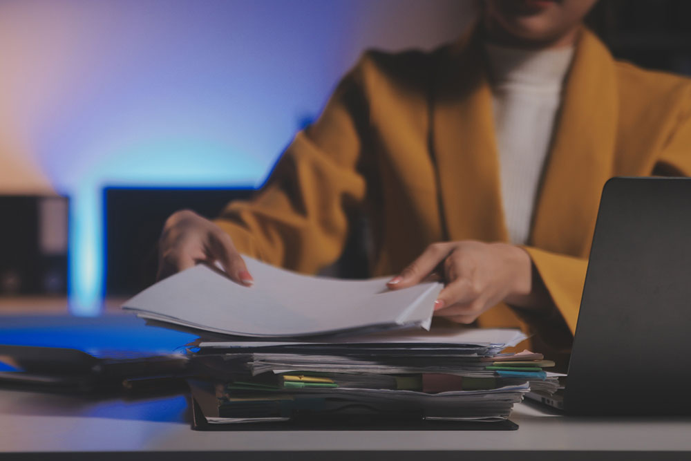 Person using a calculator to estimate financial losses and damages at a desk