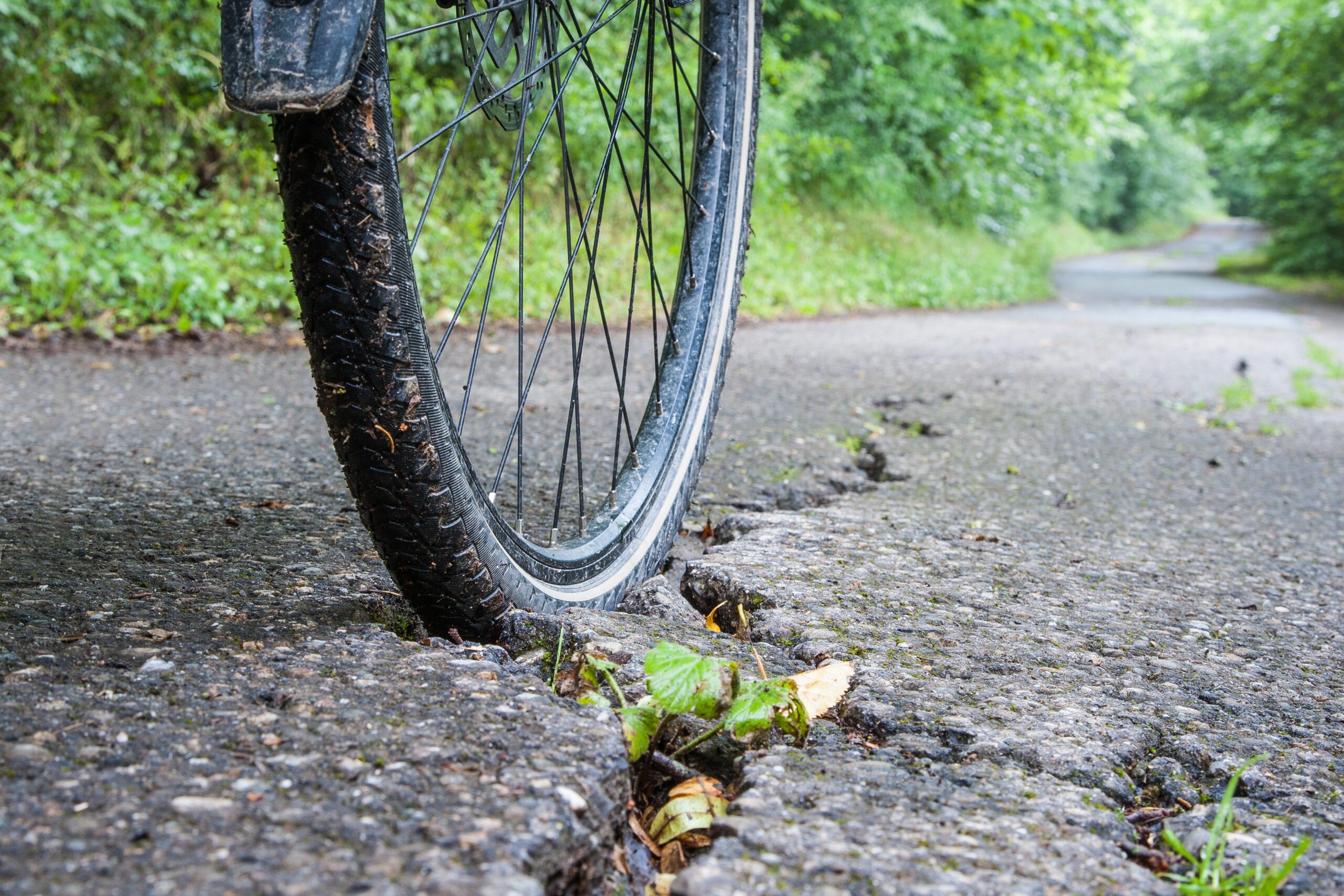 Bicycle wheel caught in cracked road surface representing dangerous road conditions causing bicycle accidents in Tampa