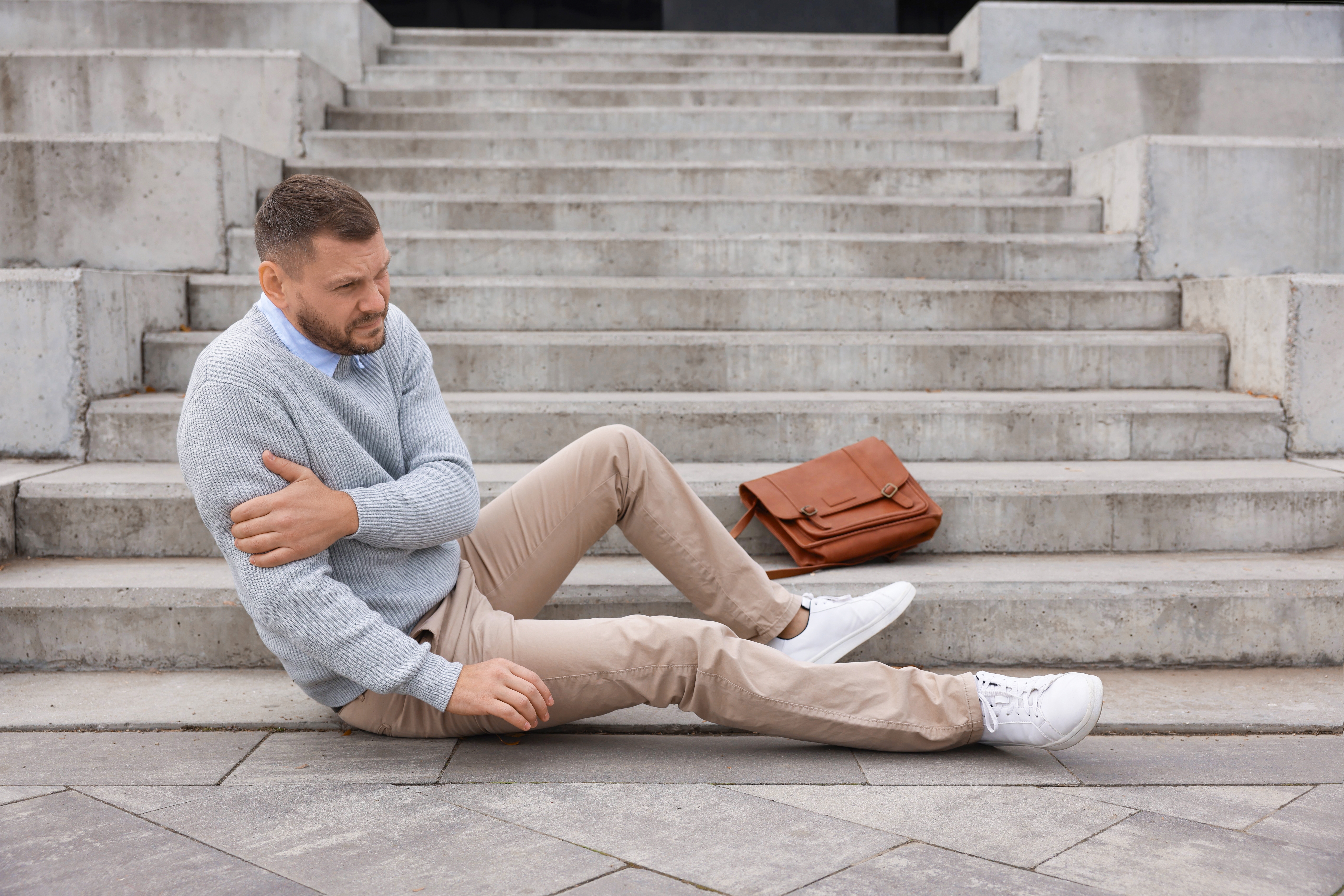 Injured man sitting on steps after a fall representing slip and fall accident evidence in Tampa