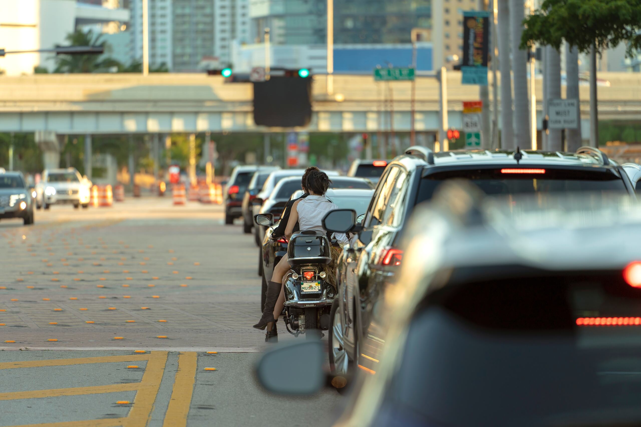 A motorcycle and passenger navigating heavy city traffic in Florida, highlighting the risks that can lead to undervalued accident settlements.