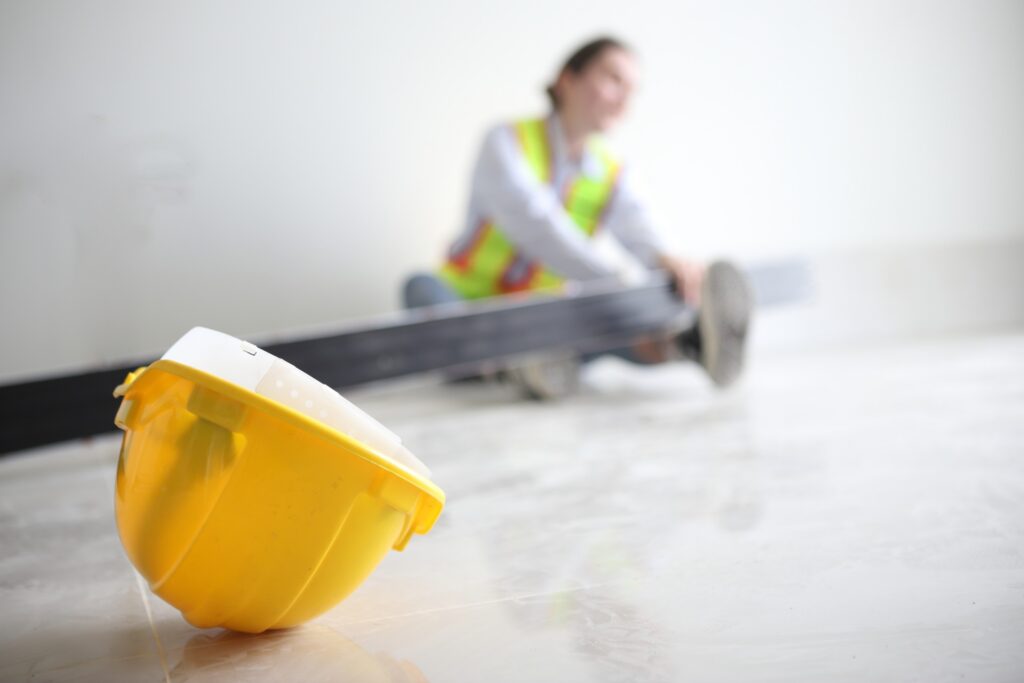 Injured construction worker sitting on the ground with safety helmet nearby, highlighting a case a Clearwater construction accident lawyer can handle