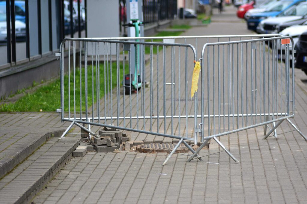 Metal barricade blocking broken sidewalk bricks involving Safety Harbor pedestrian accidents and government liability.