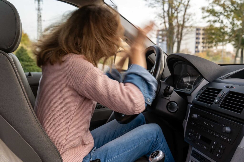 A frustrated woman gesturing wildly behind the wheel depicts aggressive driving and road rage accidents in Safety Harbor.