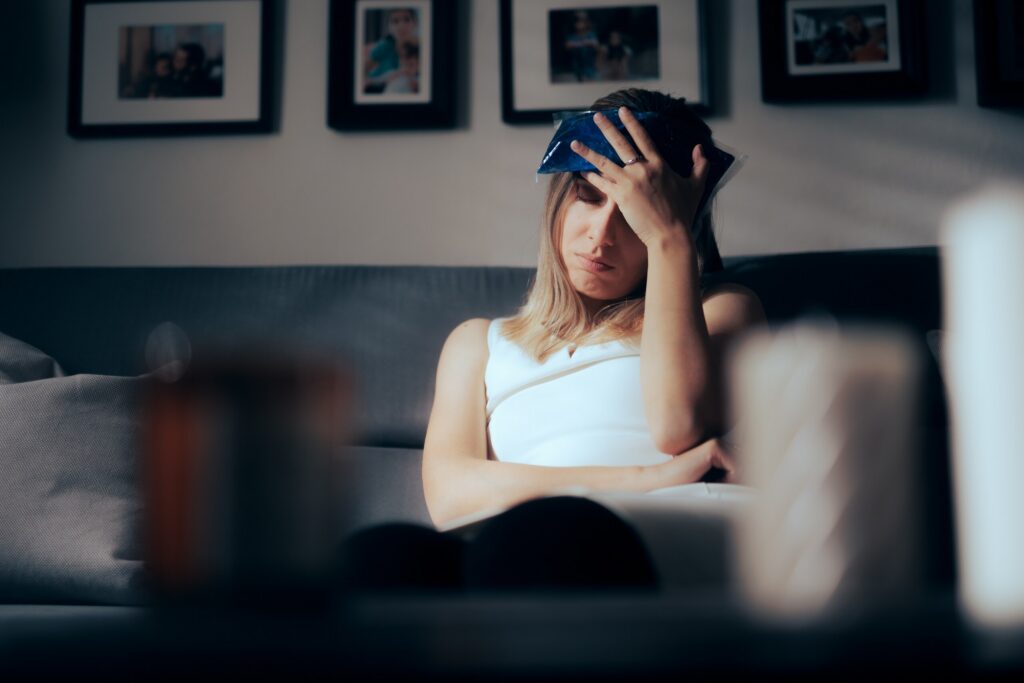 A woman holding an ice pack to her forehead depicts painful head trauma linked to Safety Harbor Concussion & Mild TBI Claims.