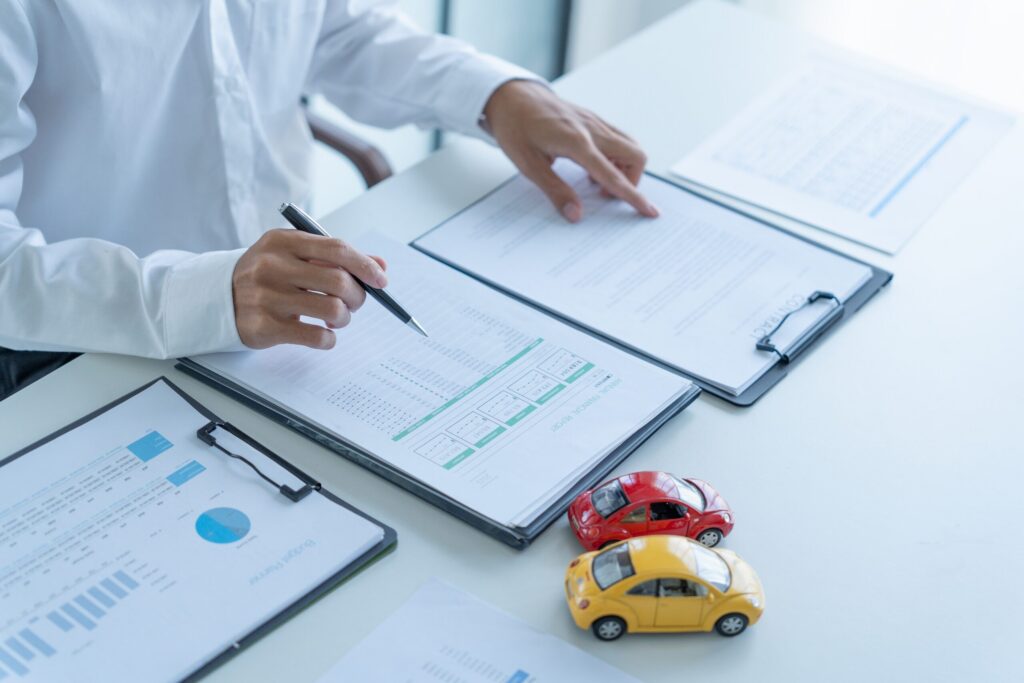 A professional reviews insurance claim documents beside model cars to evaluate a DUI Accident in Safety Harbor: PIP Recovery.