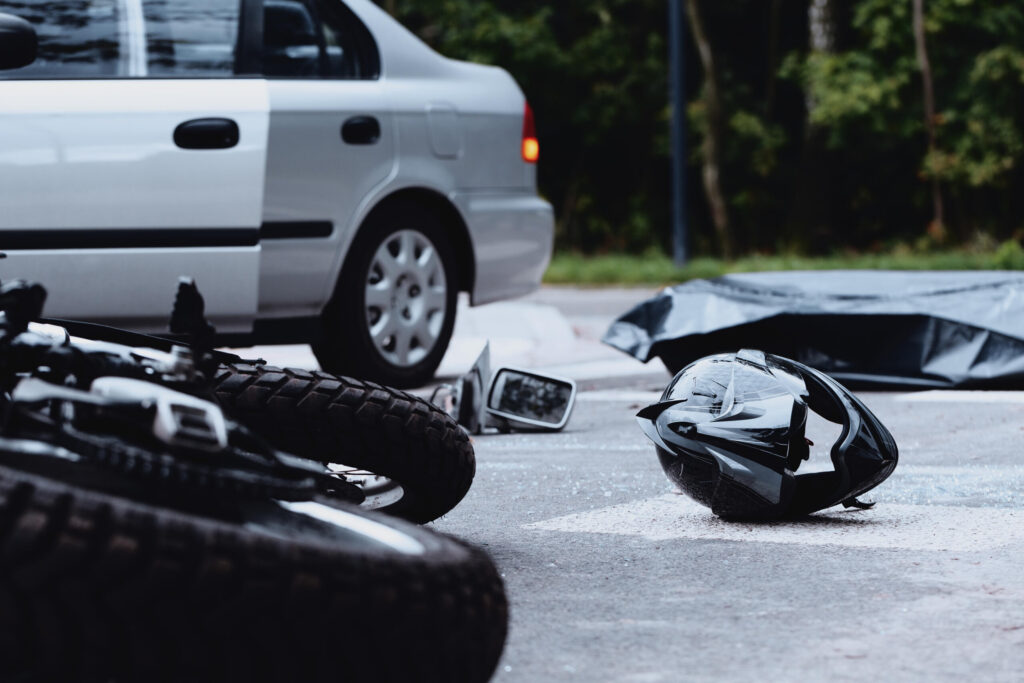 Crash scene debris with a motorcycle helmet on the pavement illustrating Why Florida PIP Doesn't Cover Your New Port Richey Motorcycle Accident.