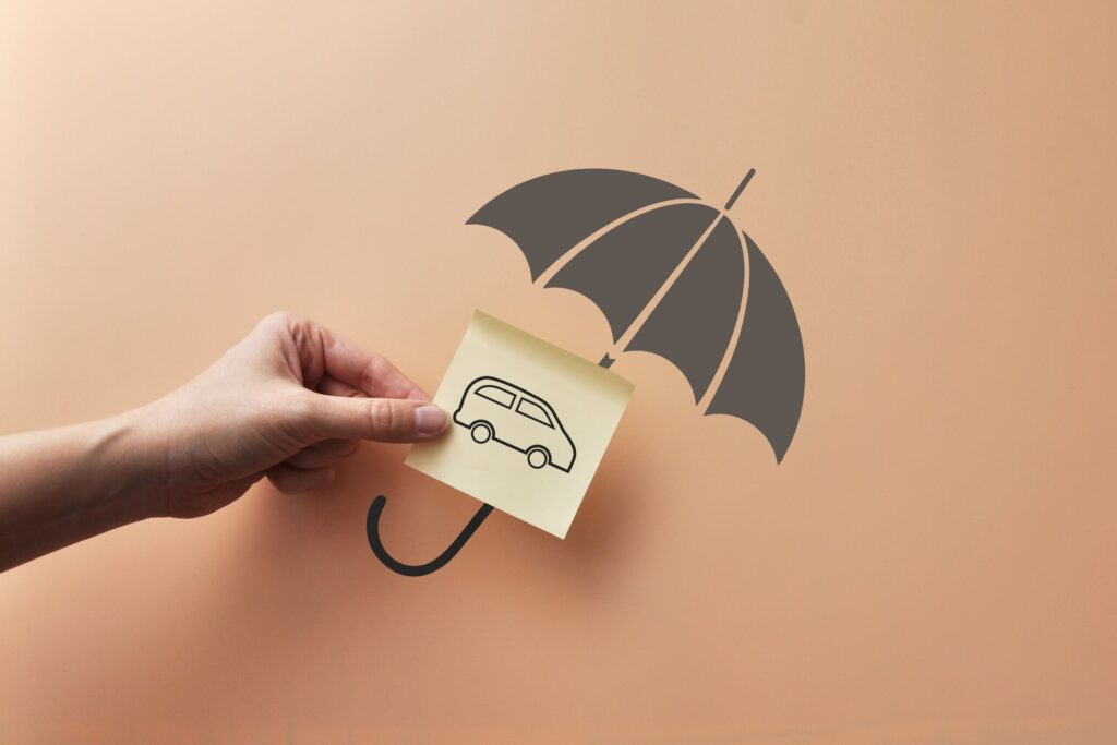 A hand holding a car drawing under a paper umbrella explaining How Florida's No-Fault Car Insurance System Works After a Clearwater Accident.