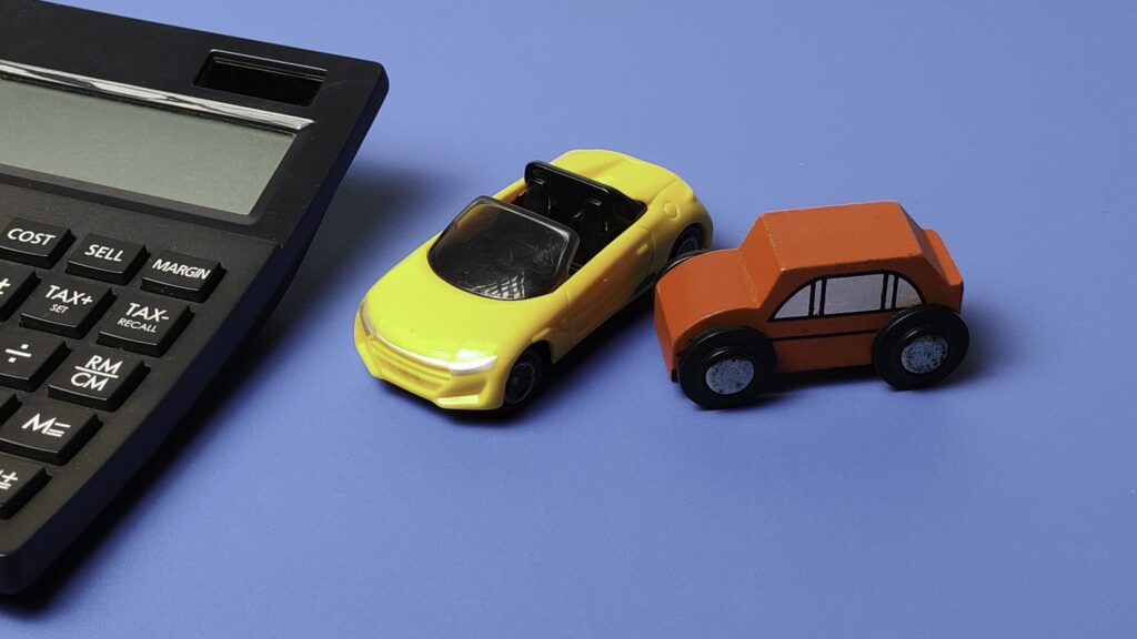 Toy cars in a fender bender collision next to a calculator showing How Florida's No-Fault Car Insurance System Works After a Clearwater Accident.