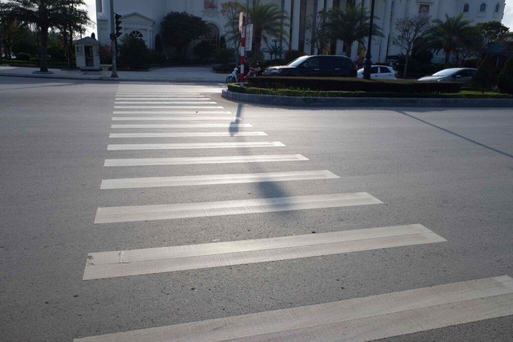 Empty marked pedestrian crosswalk painted across a wide city street.